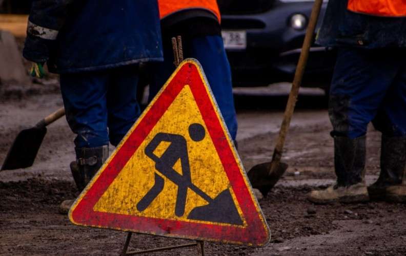 Знак, предупреждающий о земляных работах, и рабочие с лопатами