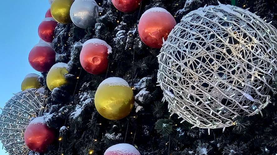 Серебристые, красные и жёлтые шары на уличной новогодней ёлке