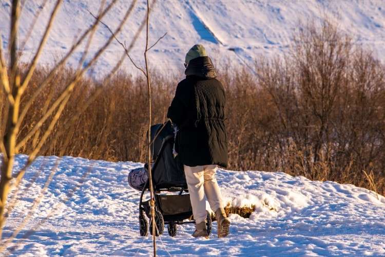 мать зимой гуляет с ребёнком в коляске