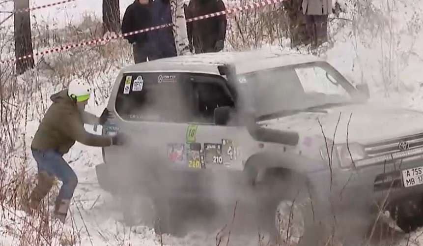 Мужчина пытается вытолкнуть машину из сугроба