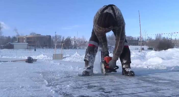 работник режет лёд бензопилой