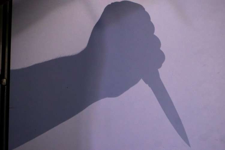 Тень на стене от руки с ножом