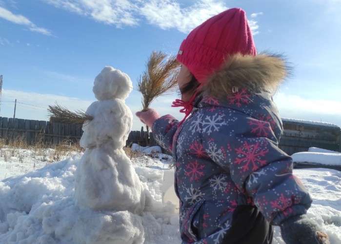 Девочка лепит снеговика