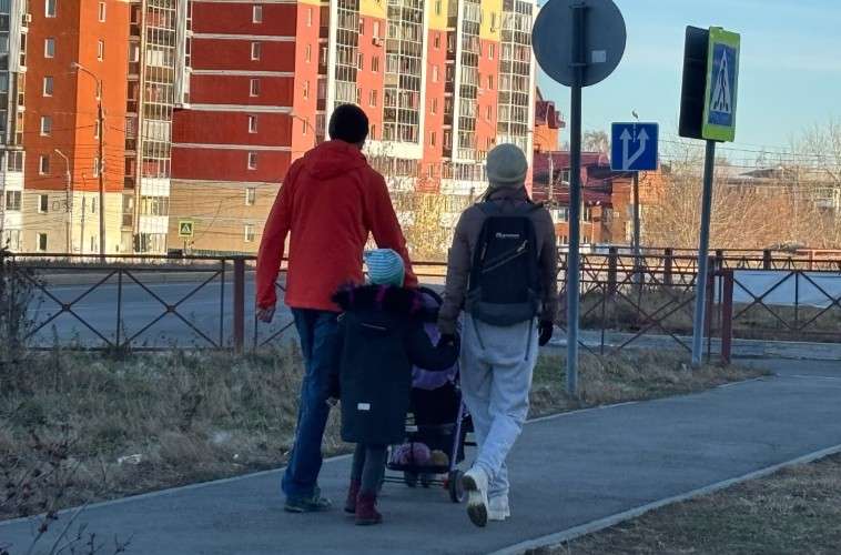 Семья с коляской идёт по тротуару