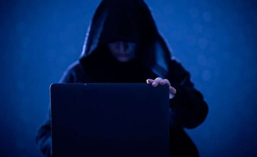 Человек с тёмном капюшоне за ноутбуком