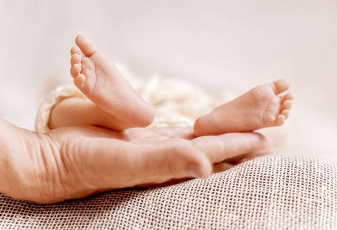 Ножки новорождённого ребёнка наруке у взрослого