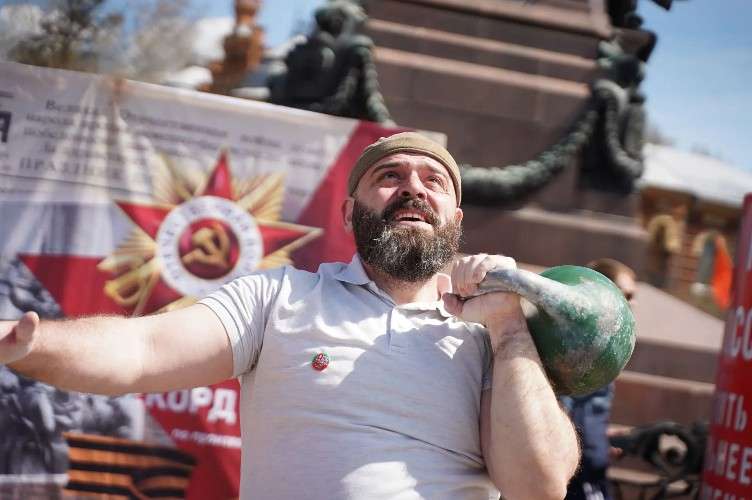 поднимает гирю
