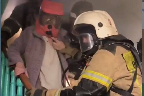 Спасатель выводит человека из горящего дома
