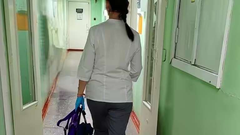 Женщина в медицинской униформе идёт по коридору