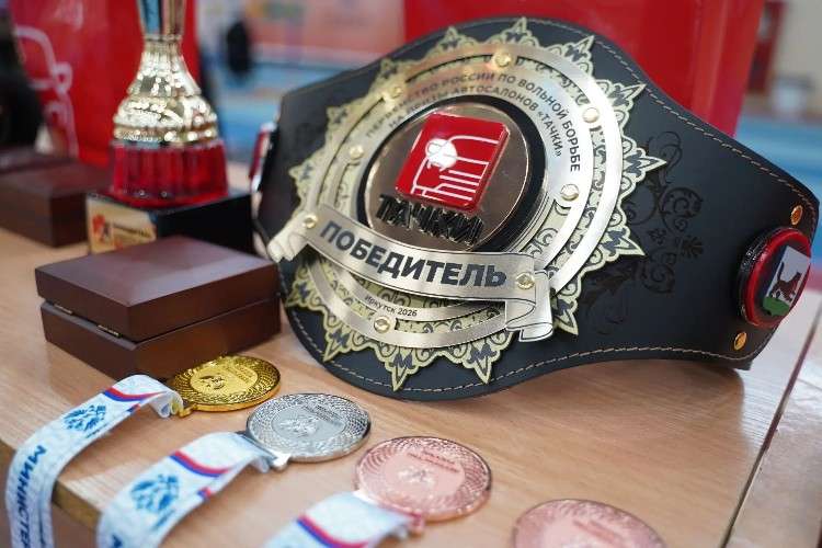 пояс чемпиона на котором написано победитель, ряд медалей и кубок на заднем плане