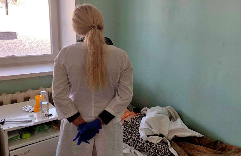 Врач смотрит на пациента в палате.