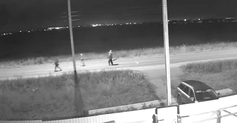 Вид с охранной камеры ночью на пустую улицу, по которой бегут три подростка