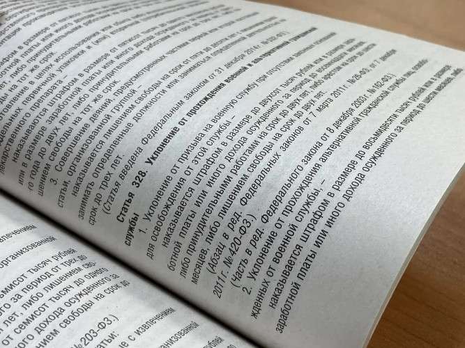 Открытая книга с текстом на русском языке. В центре страницы виден заголовок «Статья 328. Уклонение от прохождения военной и альтернативной гражданской службы». Текст описывает наказание