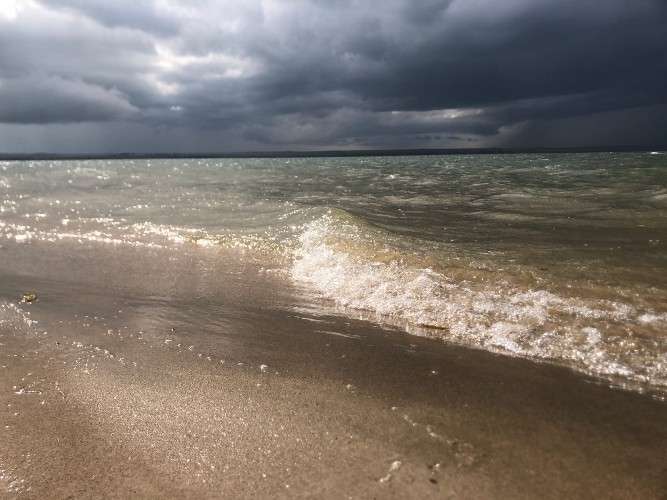 волны Братского водохранилища в грозу бьются о мокрый песчаный берег