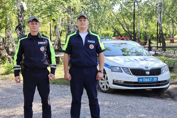 Два сотрудника на фоне машины ДПС