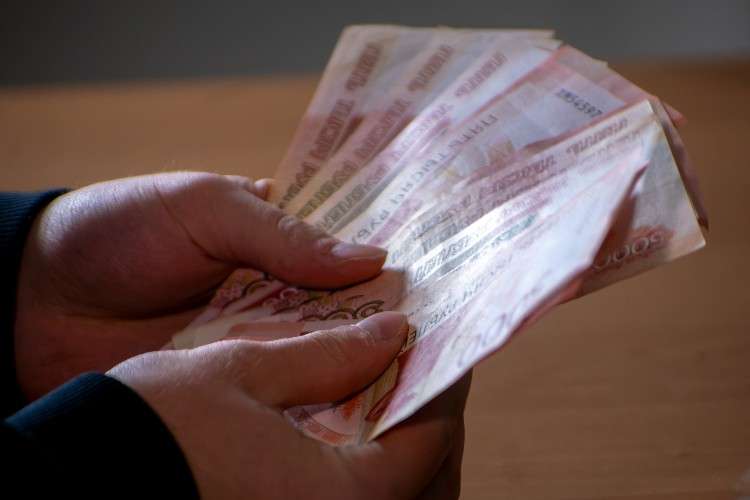 Руки человека пересчитывают веером пачку российских купюр номиналом 5000 рублей