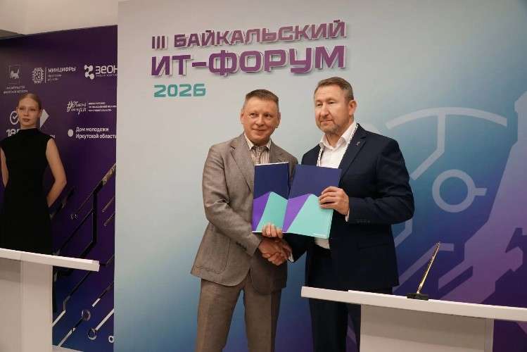 Двое мужчин в деловых костюмах пожимают друг другу руки и держат сине-бирюзовые папки, символизируя подписание соглашения. Действие происходит на фоне баннера «III БАЙКАЛЬСКИЙ ИТ-ФОРУМ 2026».