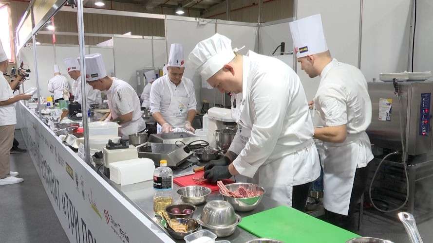 Несколько поваров готовят блюда за длинным столом