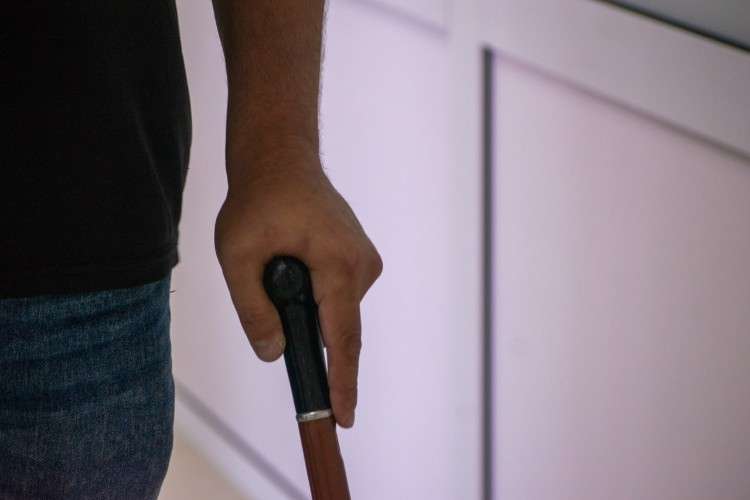 мужчина в чёрной футболке и джинсах опирается на трость