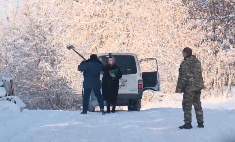 Мужчина с лопатой стоит возле женщины у машины