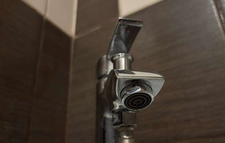 Смеситель на фоне коричневого кафеля