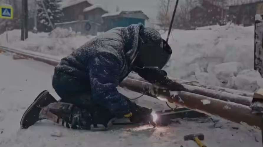Сварщик варит водопроводную трубу в Бодайбо