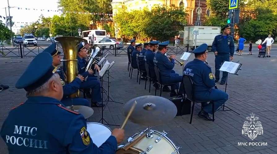 духовой оркестр МЧС играет, сяда на стульях посреди площади у памятника Александру III в Иркутске