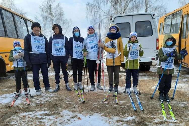 Семья стоит в ряд на лыжах, восемь человек