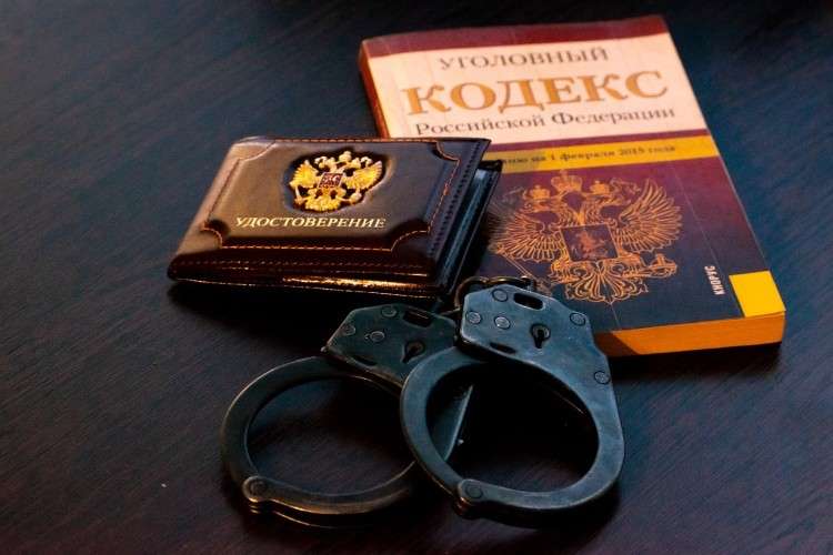 Уголовный кодекс, наручники и удостоверение лежащие на столе