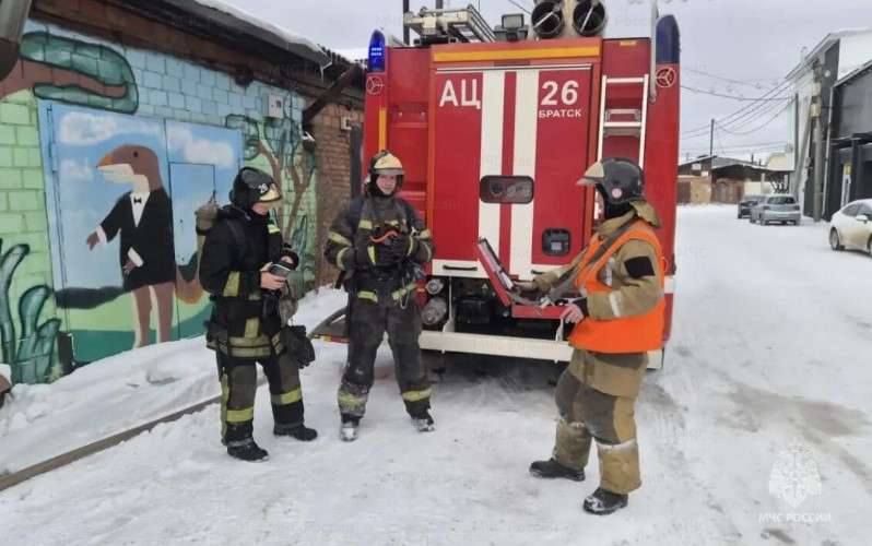Пожарные стоят возле машины МЧС в гаражном кооперативе