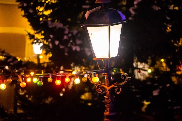 Уличный фонарь с новогодней гирляндой на фоне ёлки